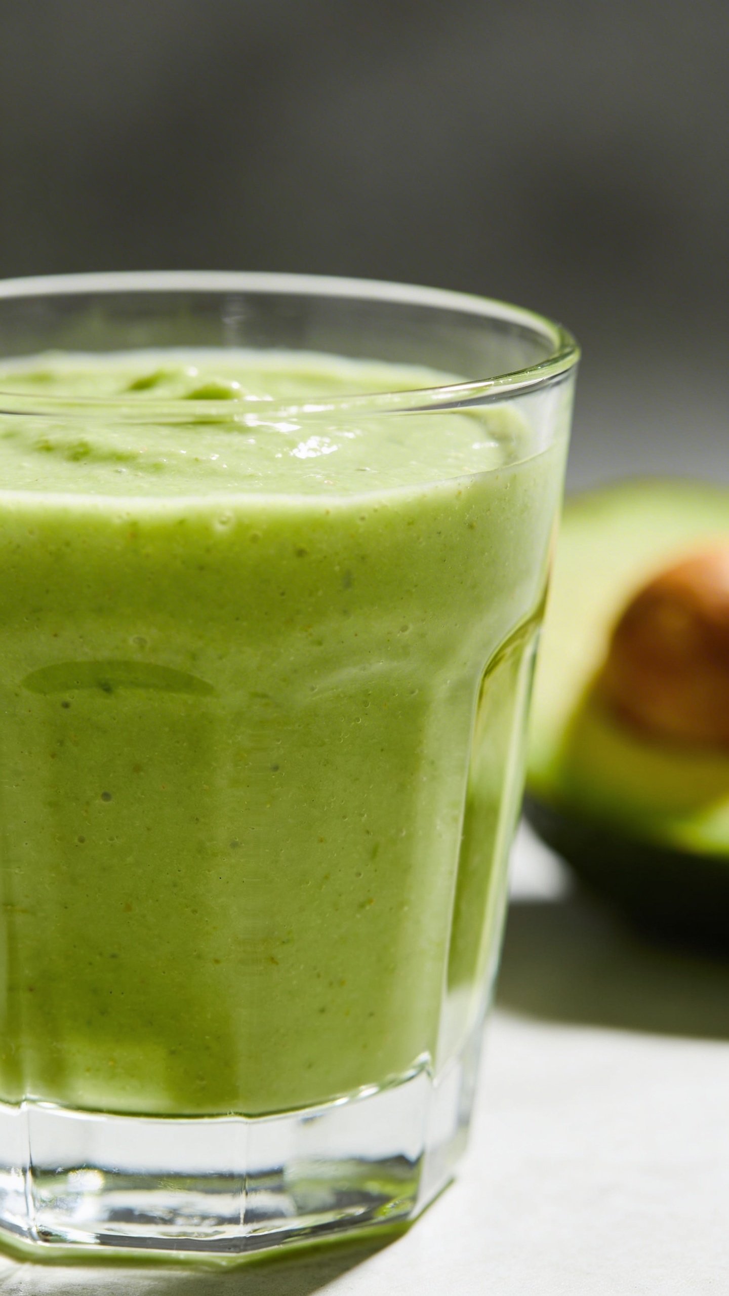 Closeup avocado protein smoothie in clear glass, minimal background