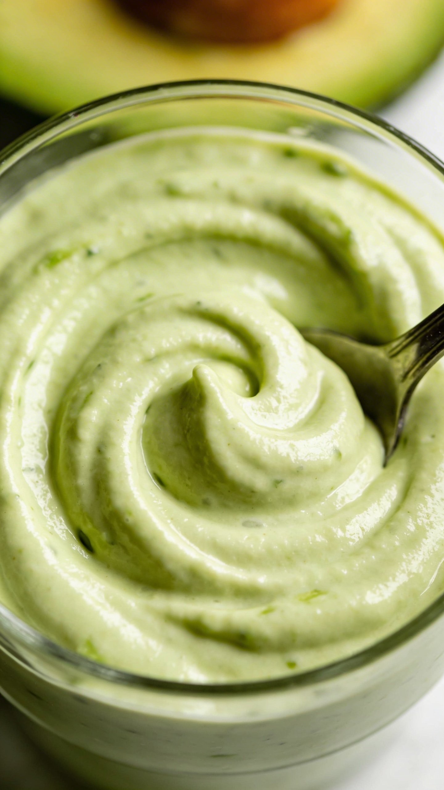 Overhead spoonable avocado smoothie swirl, natural texture, clean surface