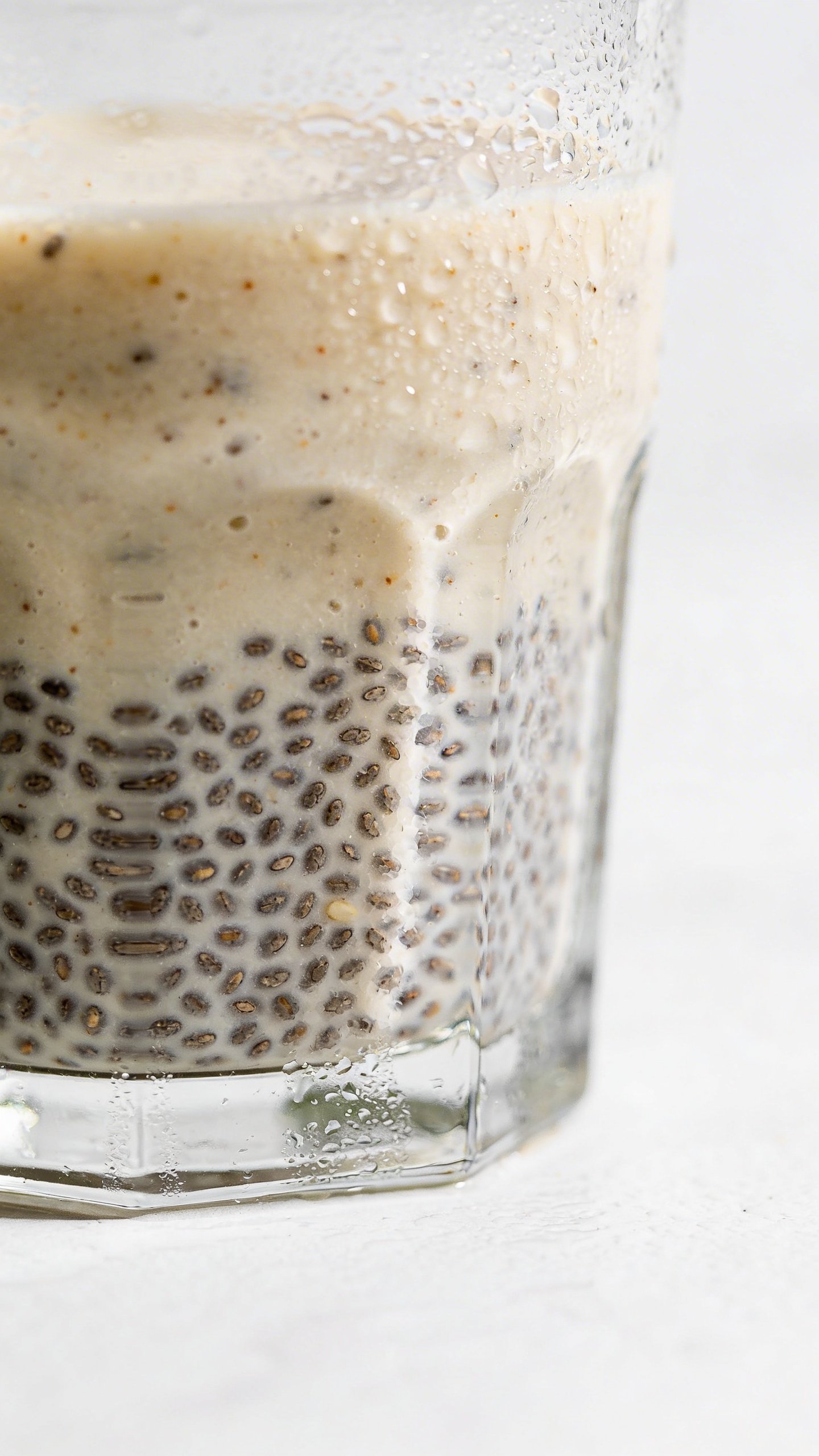 Chia-flecked pear ginger smoothie, condensation on glass, clean backdrop