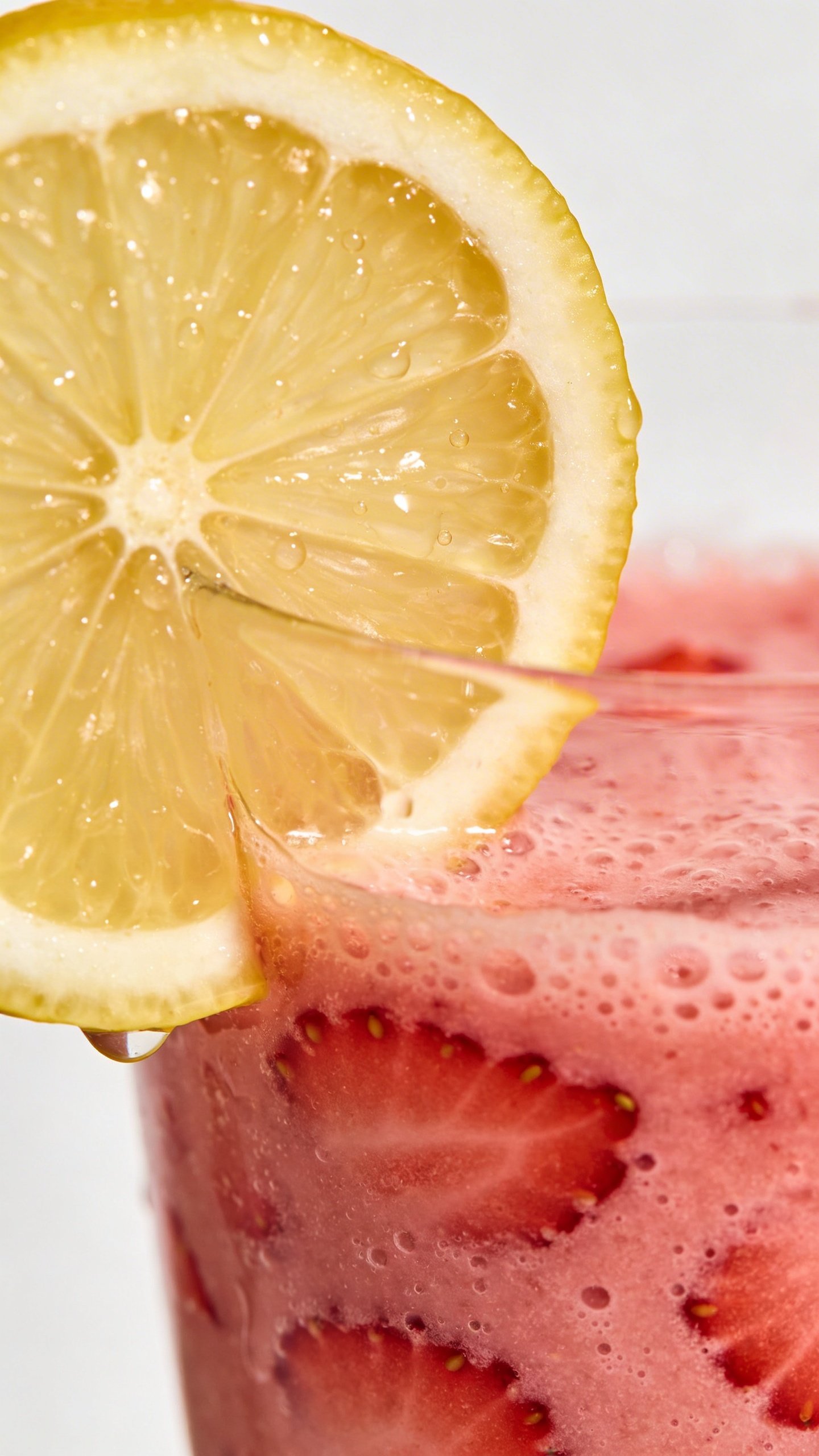 Macro shot lemon wedge garnish on strawberry smoothie, clean backdrop