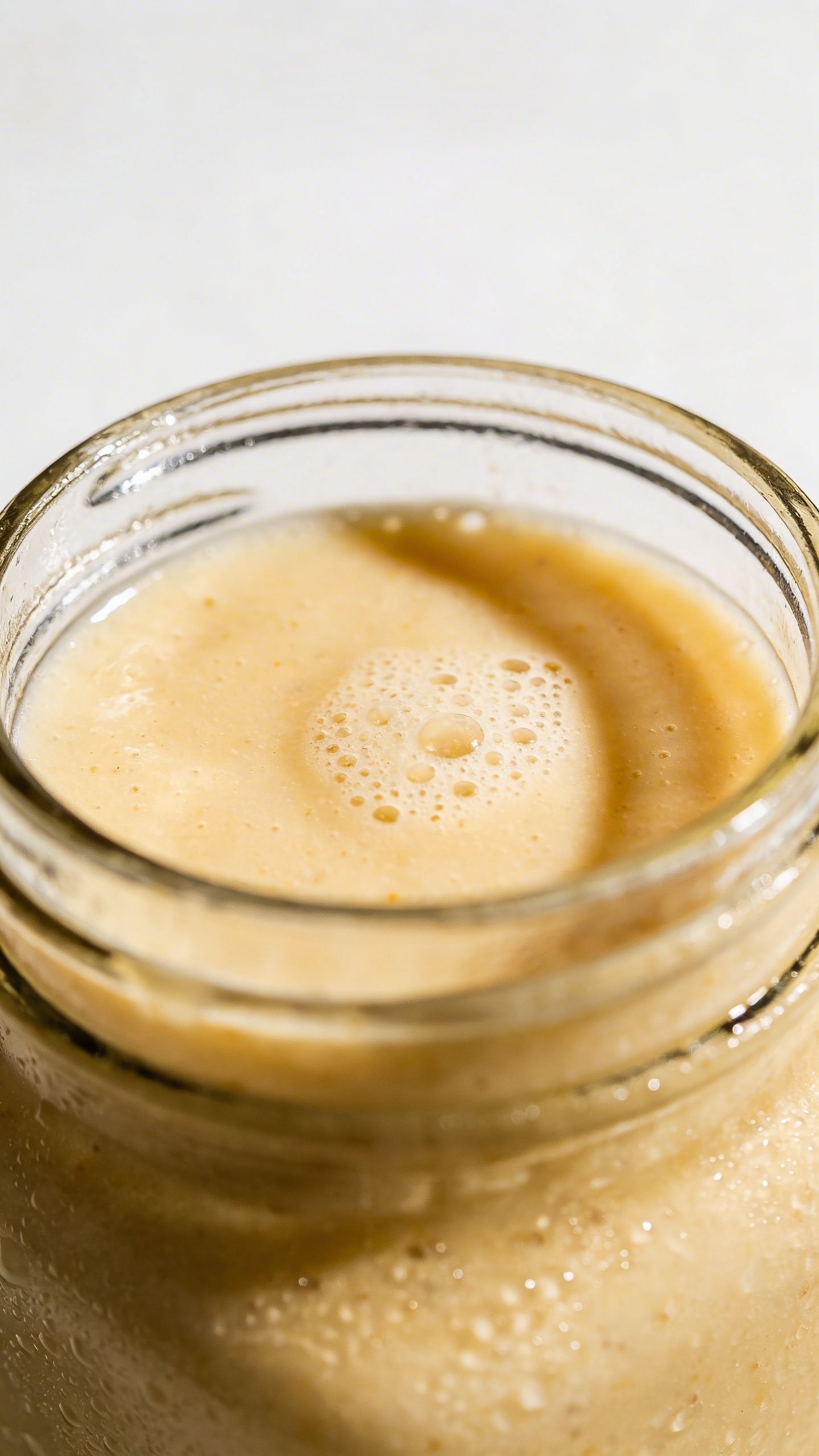 Close-up frozen banana smoothie, thick swirl, glass jar, minimal backdrop