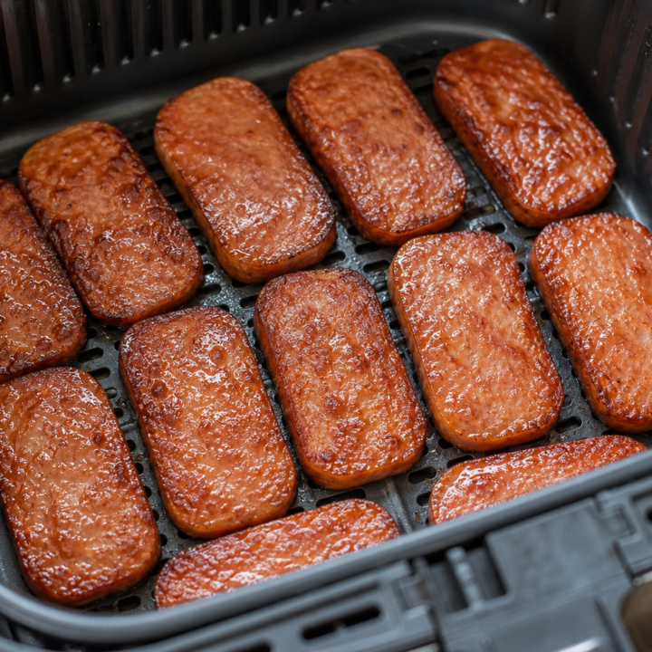 Brown sugar-glazed Spam slices with crisp edges inside an open air-fryer basket
